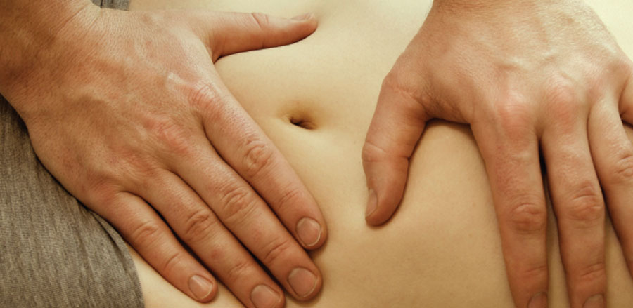 Physician palpating a patient's abdomen