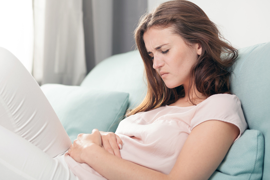 Woman lying on a sofa in discomfort