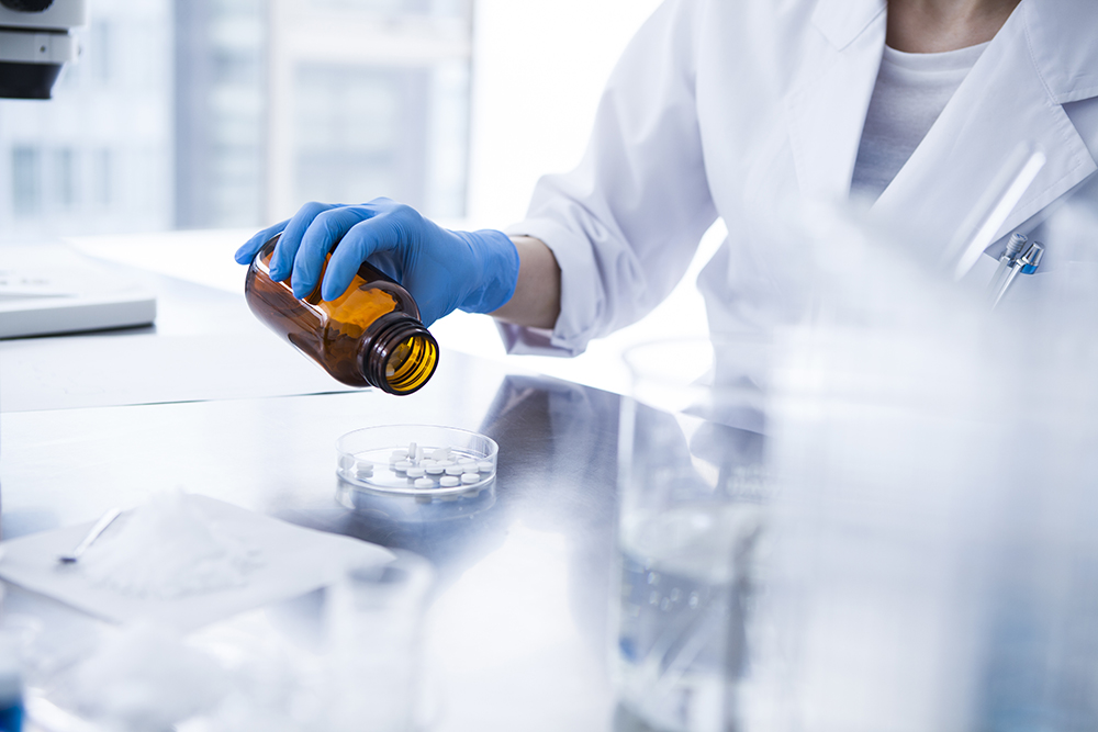 Researcher with a blue glove holding a bottle in a laboratory