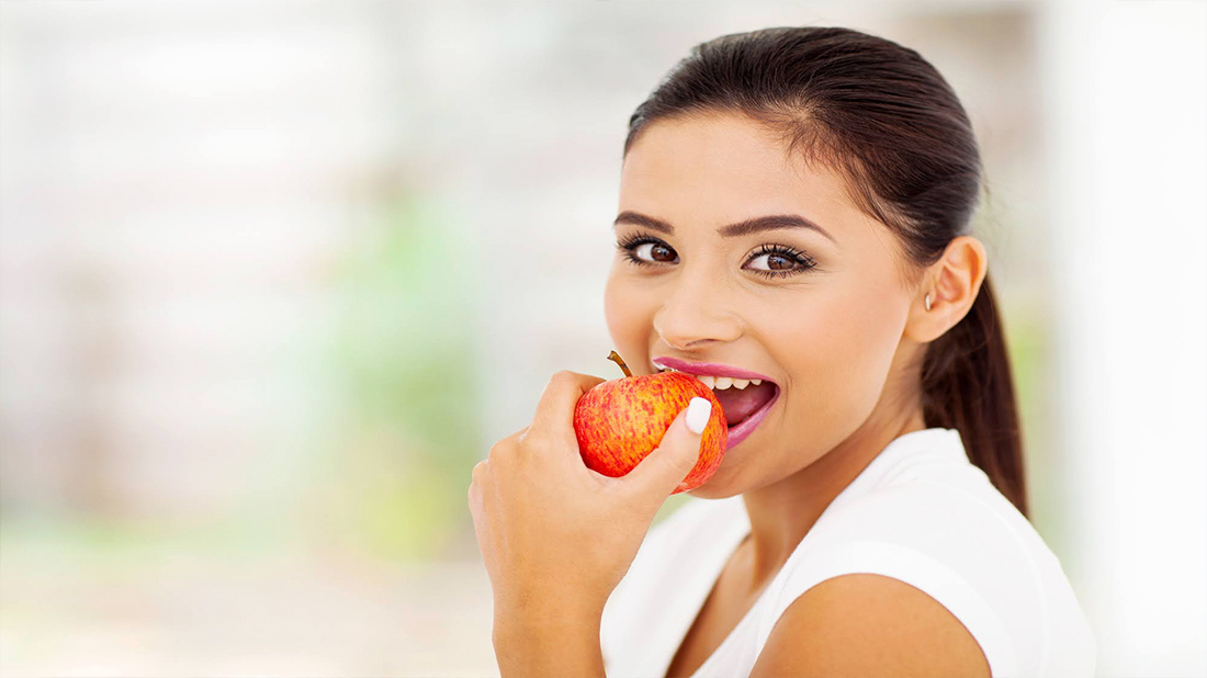 A woman biting into an apple