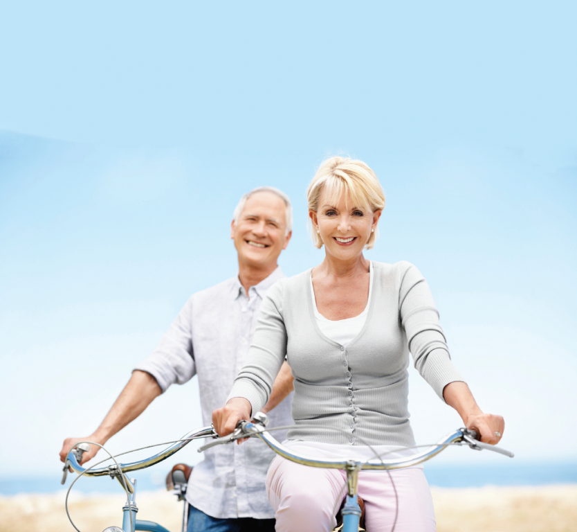 Baby Boom aged husband and wife cycling at the beach