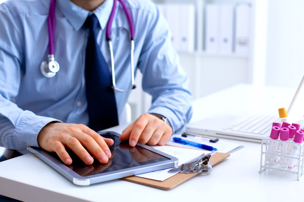 Doctor behind a desk using a tablet computer